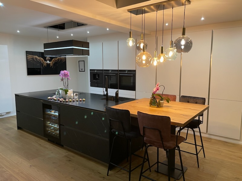 Cuisine Häcker moderne au Luxembourg avec îlot marbre foncé et colonnes blanc polaire