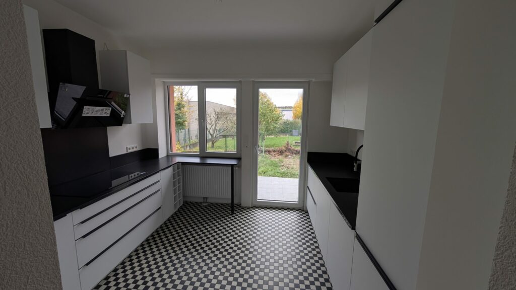 Article présentant une cuisine contemporaine installée au Luxembourg, composée de meubles Rotpunkt Zerox MA blancs, d’un plan de travail en granit noir poli, de poignées inox noir brossé et d’un électroménager Siemens haut de gamme, réalisée par Direct Cuisine.