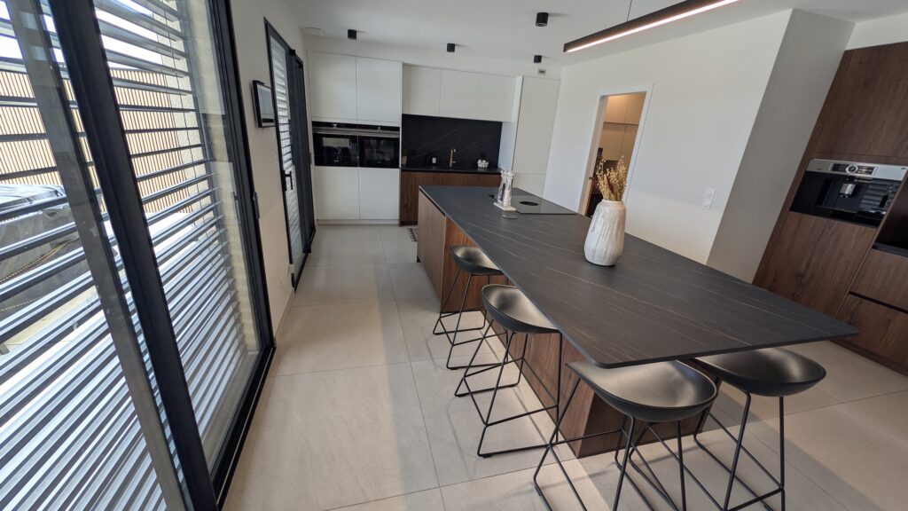 Cuisine HÄCKER en noyer 1099AV et blanc polaire 2135VV avec îlot central et plan de travail LAMINAM Noir Désir à Évrange