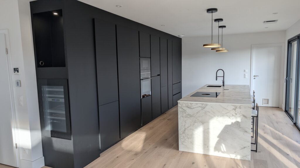 Îlot central de cuisine avec plan de travail Dekton Portum et plaque Bora dans cuisine Rotpunkt noire