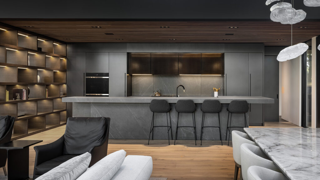 Grande cuisine moderne avec îlot gris effet pierre, meubles bois et éclairage intégré